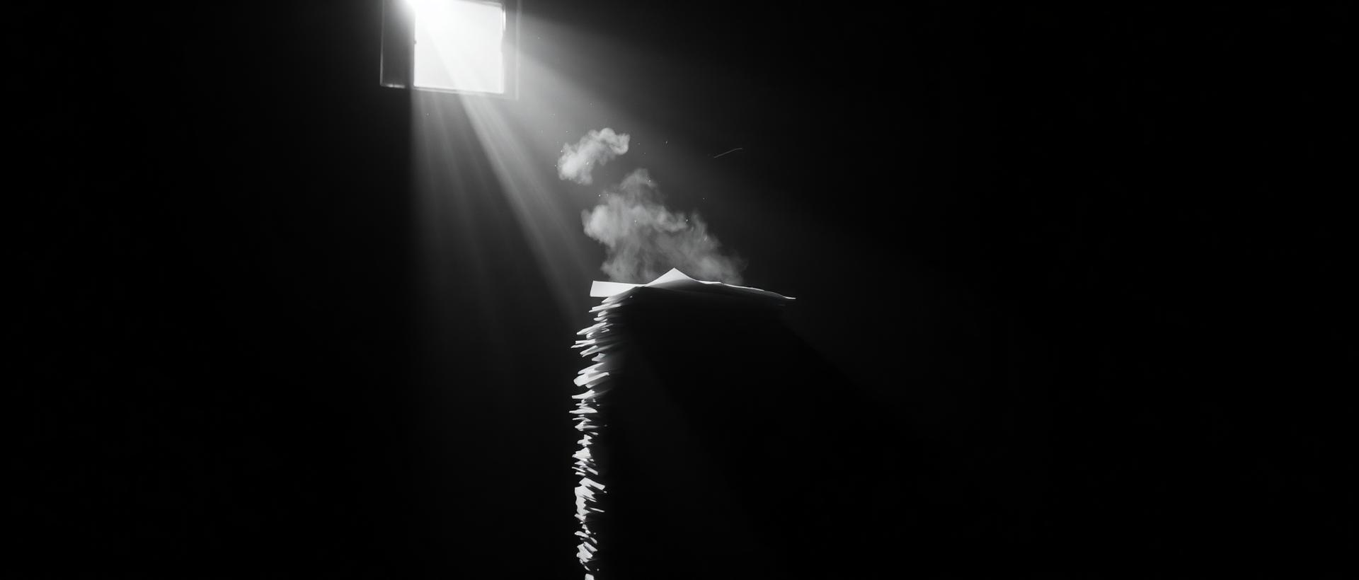 Dust in a shaft of light above a stack of paper